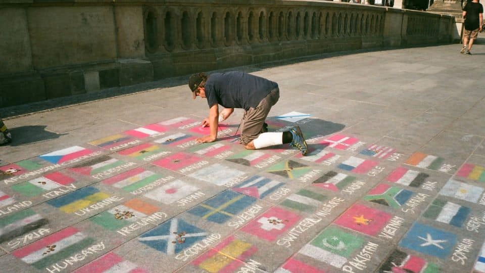 homem pintando bandeiras de vários países no chão