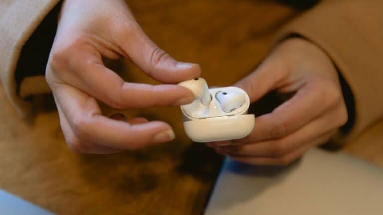 Pessoa segurando um par de AirPods com estojo de carregamento branco, examinando o dispositivo para verificar sua autenticidade